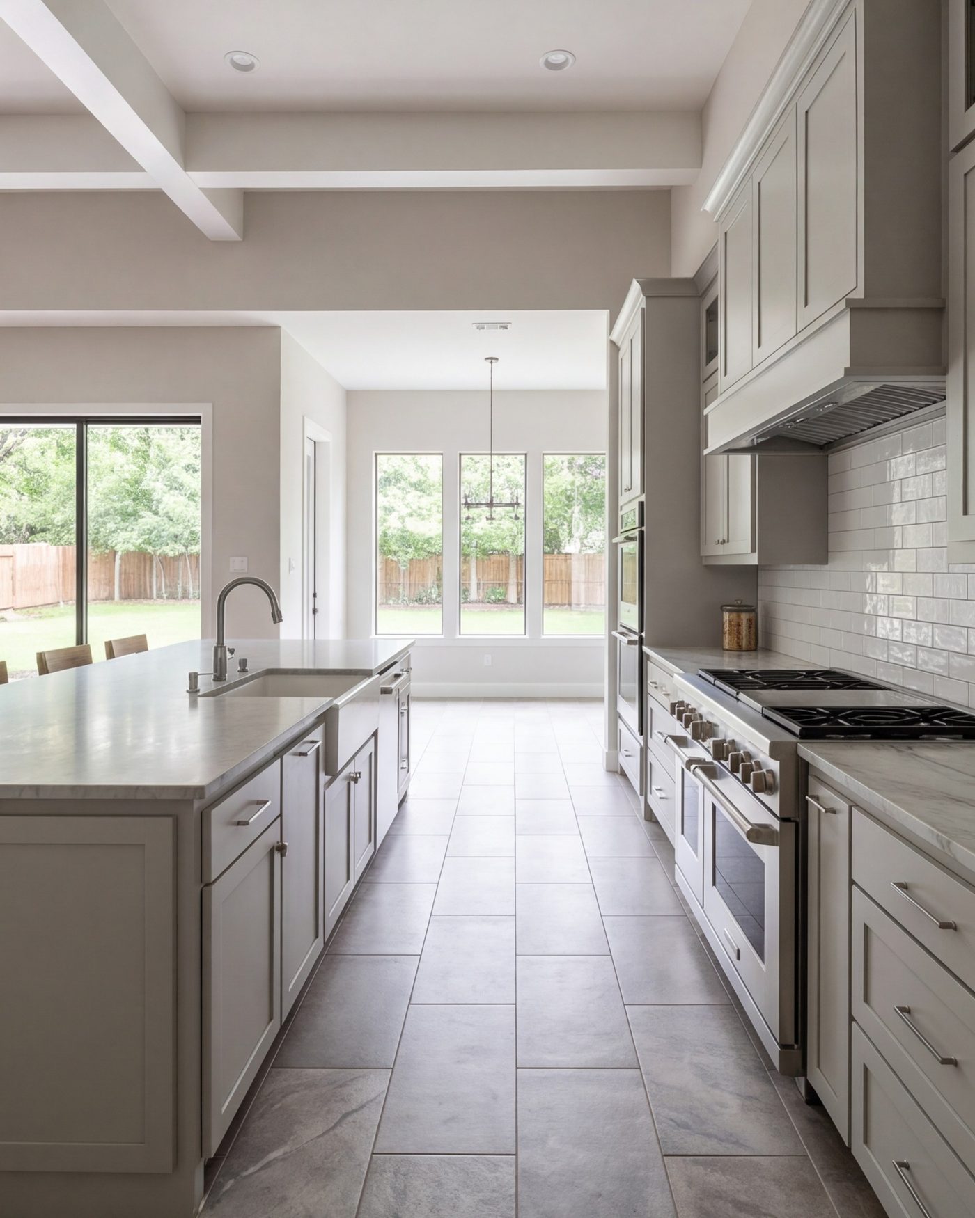 tall view down a wide kitchen aisle between island and range wall, whole room in frame